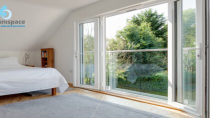 Bedroom with large glass doors and windows overlooking greenery