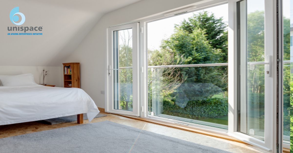 Bedroom with large glass doors and windows overlooking greenery